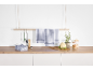 Kitchen counter with hanging and folded checkered dishcloths, vegetables, and herbs.
