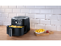 Air fryer with golden fries and a bowl of fries with tomato sauce.