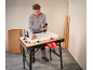 Man assembling furniture with a cordless drill on a workbench.