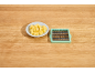 Diced potatoes on a plate next to a vegetable dicer on a wooden surface.