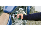 Man fastening a screw on a blue motorcycle with a screwdriver.