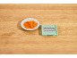Shredded carrots in a white plate and a green grater on a wooden table.