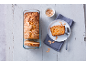 Almond and apricot loaf cake in a glass pan, with a slice on a plate