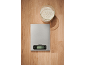 Digital kitchen scale with a bowl of flour next to it on a wooden table.