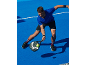 Man in blue t-shirt and black shorts playing padel with a racket and ball.