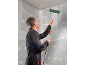Man sanding a wall with a long-handled sander, preparing it for painting.