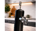 Black beverage dispenser with chrome tap on a kitchen counter.