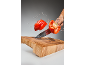 Red bell pepper being sliced mid-air with water splashes over a wooden cutting board.