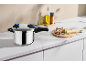 Stainless steel pressure cooker on a kitchen counter with fresh ingredients.