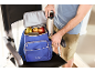 A man places a thermal bottle into a cooler backpack filled with fruit.
