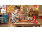 Toddler playing with toy pizza and kitchen set in a cozy room.