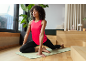 Woman in pink tank top and black leggings doing yoga on a mat.