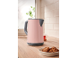 Pink electric kettle on a kitchen counter with cookies and tea.