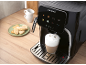 Black automatic coffee machine with touchscreen, brewing a latte, with cookies on the side.