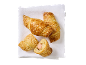 Sausage rolls with sesame seeds on white fabric, shot from above.