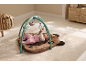 A baby playing on an activity mat with hanging toys in a bright room.
