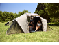 Family camping in a large tent with a portable cooler and camping chairs.