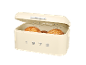 Cream-colored bread bin with an open lid, containing three round loaves of bread. The year '1973' is embossed on the front.