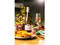 Bottle of sparkling wine and glass with strawberry on festive table with Christmas decorations.