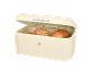 Beige bread bin open with three loaves of bread inside.