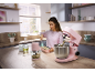 Woman in kitchen preparing food with pink stand mixer and chopper.