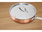 Copper pan with a stainless steel lid on a wooden surface.
