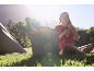 Woman sitting by a portable cooler and tent in nature.