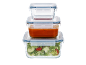 Stacked glass food storage containers, one with tomato sauce, another with salad.