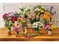 A vibrant display of various fresh flowers in vases on a wooden table, including tulips, lilies, and roses.