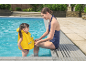 Adult helping child in a yellow swim vest in a swimming pool.
