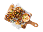 Roasted potatoes with spring onions and creamy dip on a wooden board.