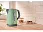 Green electric kettle with grey details in a kitchen with a wooden countertop and white tiles.
