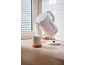 White electric kettle pouring hot water into a mug on a wooden countertop.
