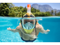 Woman in a full-face snorkel mask swimming in a pool with mountains in the background.