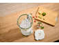 Blender with ice cubes, limes, raspberries, and a glass of refreshing drink on a wooden table.