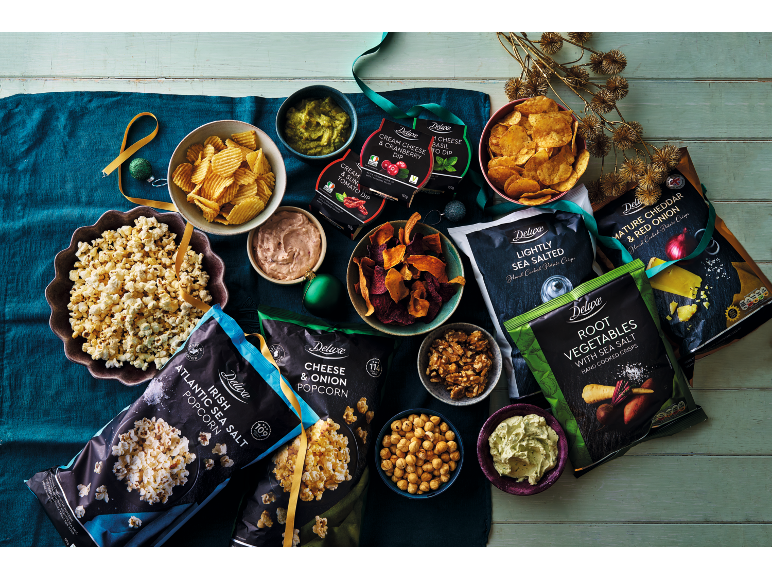 Assortment of crisps, popcorn, and dips on a festive table.