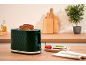 Green toaster with toasted bread, accompanied by tomatoes and a plate with fresh cheese.