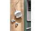 White wireless earbuds with an open charging case and cable, next to a laptop.