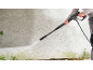 Person cleaning a textured wall with a pressure washer, removing dirt and grime.