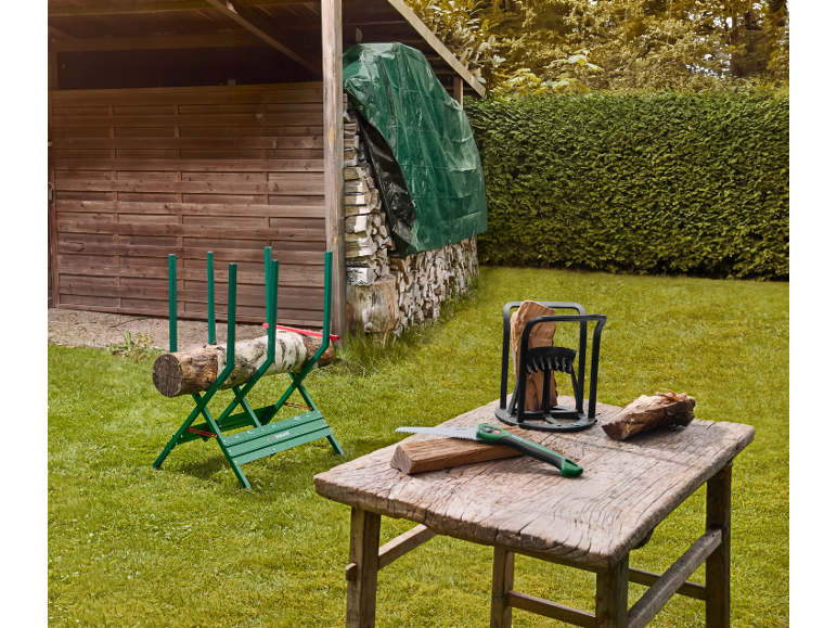 Wood sawhorse and log splitter in a garden, with a saw and wood on a table.