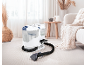 Carpet cleaner with hose and nozzle on a light carpet in a cozy living room.