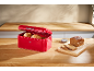 Loaf of bread and rolls in a red bread box on a wooden counter.