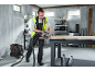 Man cutting a wooden board with a circular saw in a workshop, with a vacuum cleaner nearby.