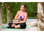Woman sitting on yoga mat, using massage gun, green slides next to her.