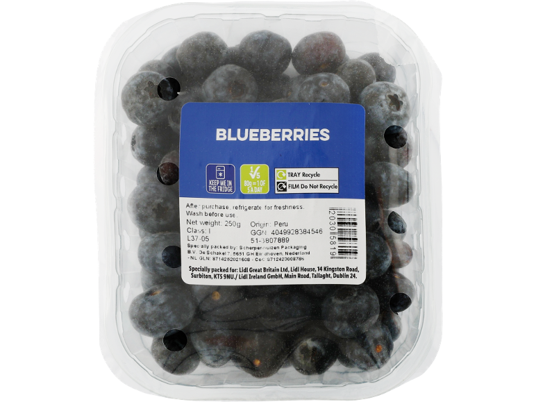 A clear plastic container of fresh blueberries with a blue label detailing product information.