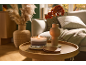 Burning candle and vase with autumn flowers on a wooden table in the living room.