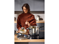 Woman serving soup from a pressure cooker into a bowl in a modern kitchen.