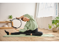 Woman in CRIVIT sweatshirt and leggings exercising with a pilates ring on a mat.