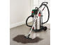 Industrial vacuum cleaner with hose and nozzle cleaning dirt from the floor.