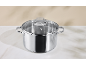 Stainless steel pot with a glass lid and volume markings on a marble countertop.